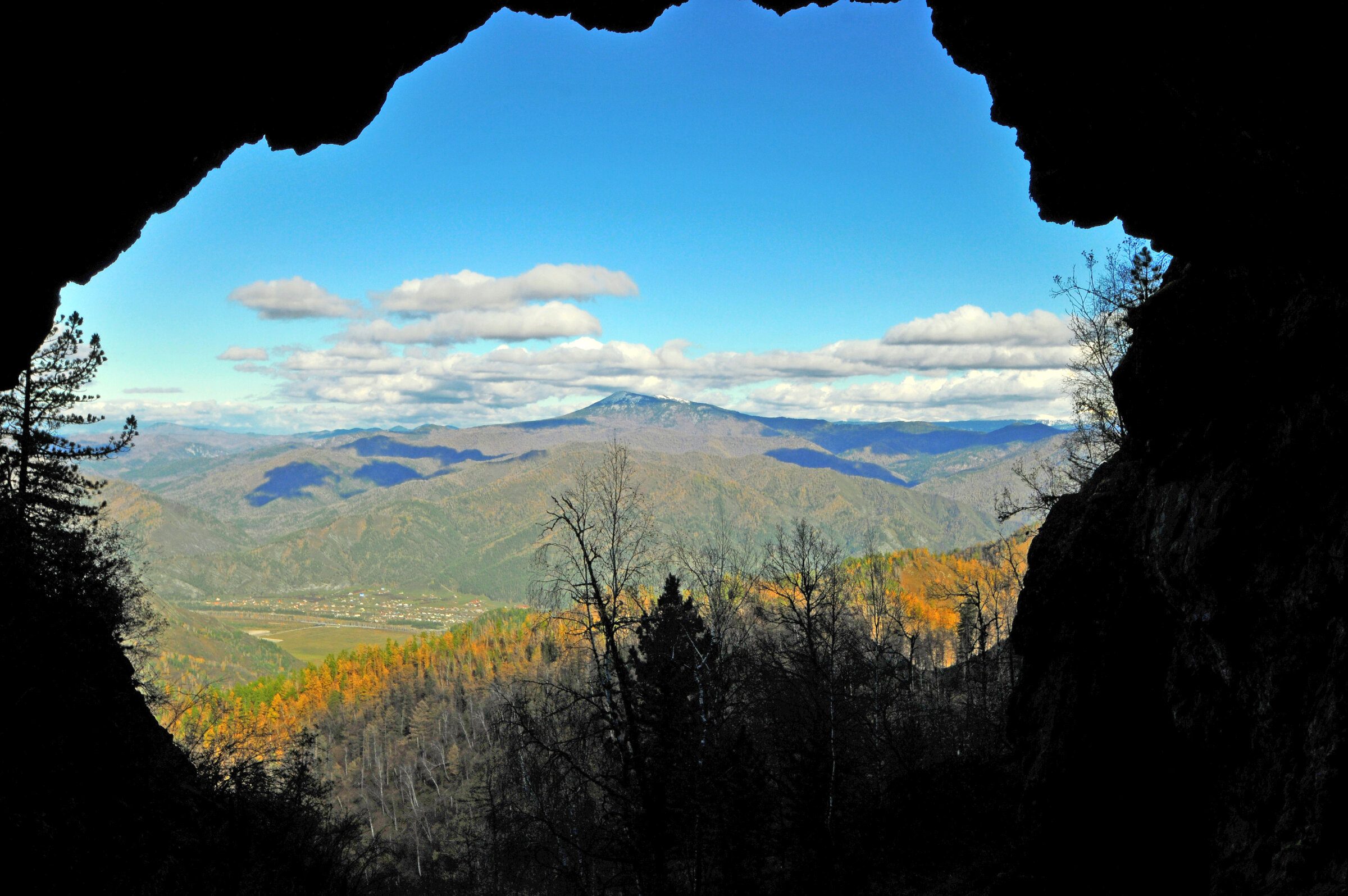 вид из пещеры осенний лес горы голубое небо облака